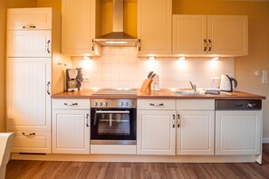 A modern kitchen with white cabinetry, a built-in oven, a coffee maker, and a sink.