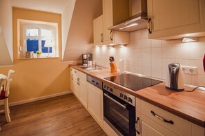 A modern kitchen with white cabinets, a wooden countertop, a built-in oven, and a window with a view of the outside.