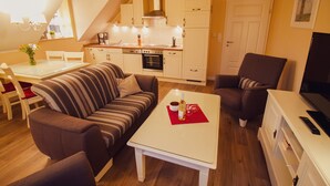 Ein gemütliches Wohnzimmer mit einem gestreiften Sofa, einem weißen Couchtisch und einem Fernsehschrank.