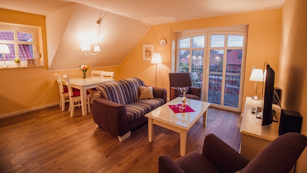 A cozy living room with a sofa, a dining table, and a TV. - Int Corner 7 (Krummhörn)
