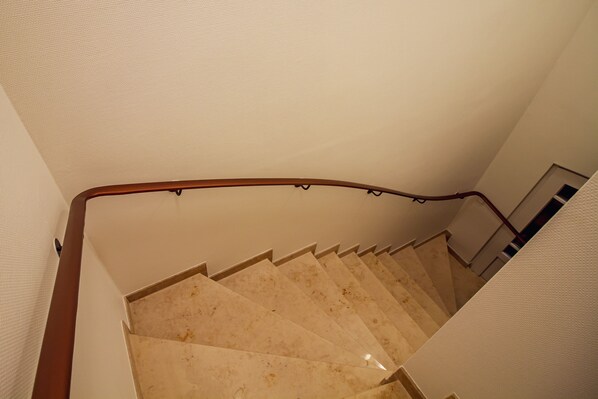 A staircase with a wooden handrail and beige steps. - Int Corner 8 (Krummhörn)