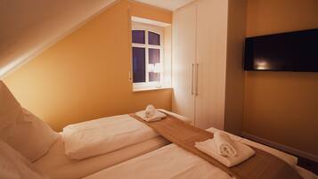 A hotel room with two beds, a window, a TV, and a wardrobe.