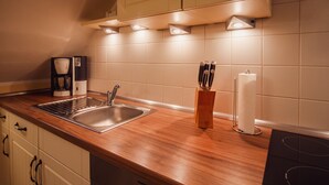 Una cocina con pileta de acero inoxidable, encimera de madera y salpicadero de azulejos blancos.
