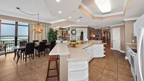 A spacious kitchen with a large island, a dining area with a view, and a modern ceiling design. - Phoenix West 2101 | 4BR/4BA Gulf-Front Condo | Oversized Balcony + Lazy River (Orange Beach)