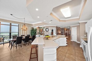 A spacious kitchen with a large island, a dining area with a view, and a modern ceiling design.