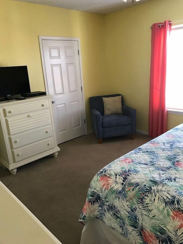 A bedroom with a bed, a dresser, a chair, and a television.