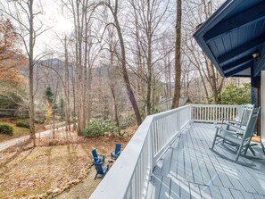 Guests can enjoy serene views of the forest from this deck, featuring Adirondack chairs and a bench.
