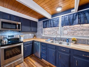 Enjoy cooking in this well-equipped kitchen with a stainless steel range hood, microwave, and large window.