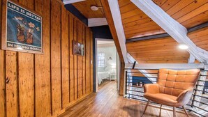 A wooden interior with a high ceiling, a leather chair, and a poster on the wall. - Balsam Retreat -Charming, Stylish, Great Location! (Maggie Valley)