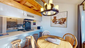 Eine moderne Küche mit Einbauherd, Kühlschrank und Mikrowelle. Es gibt einen Essbereich mit einem Holztisch und Stühlen.