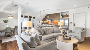 Un salon moderne avec un canapé d’angle, une table basse et un coin repas avec des chaises.