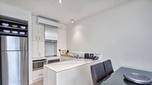 A modern kitchen with white cabinetry, stainless steel appliances, and a marble countertop.