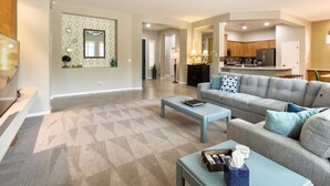 A spacious living room with a grey sofa, a coffee table, and a ceiling fan. - Modern Anthem Allure - Perfect Home Away From Home (Anthem)