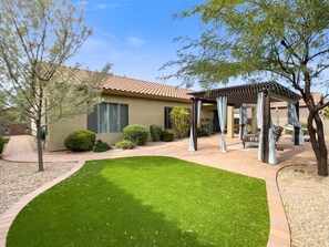 A house with a patio, a pergola, and a well-maintained lawn.