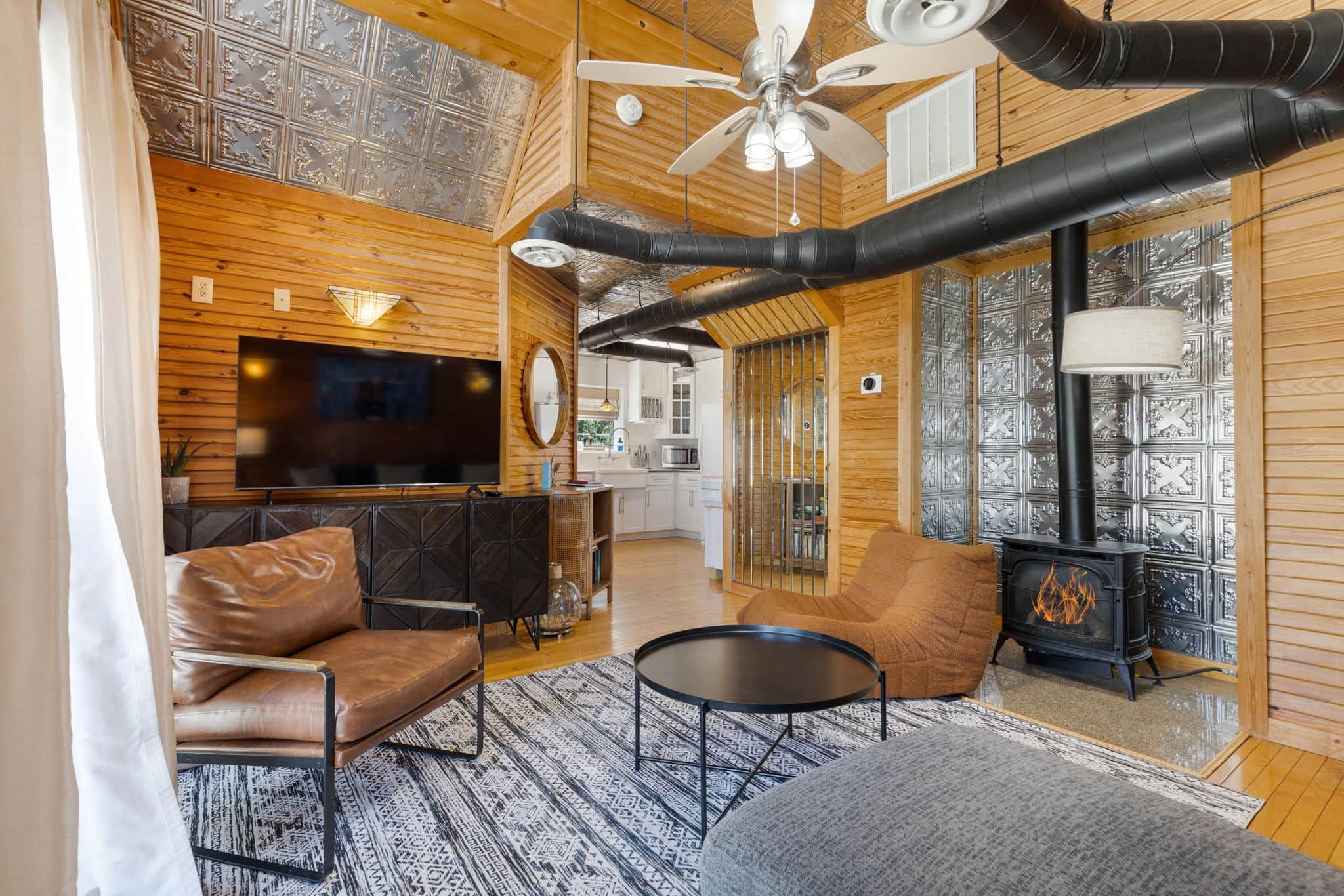 Una sala de estar acogedora con chimenea, sofá de cuero y televisor.