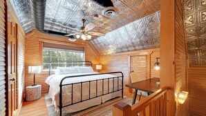 Ein Schlafzimmer mit Bett, Schreibtisch, Stuhl, Deckenventilator und Fenster.