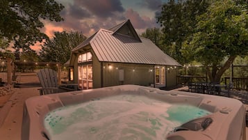 Un jacuzzi con una terraza de madera y un edificio con techo de metal al fondo.