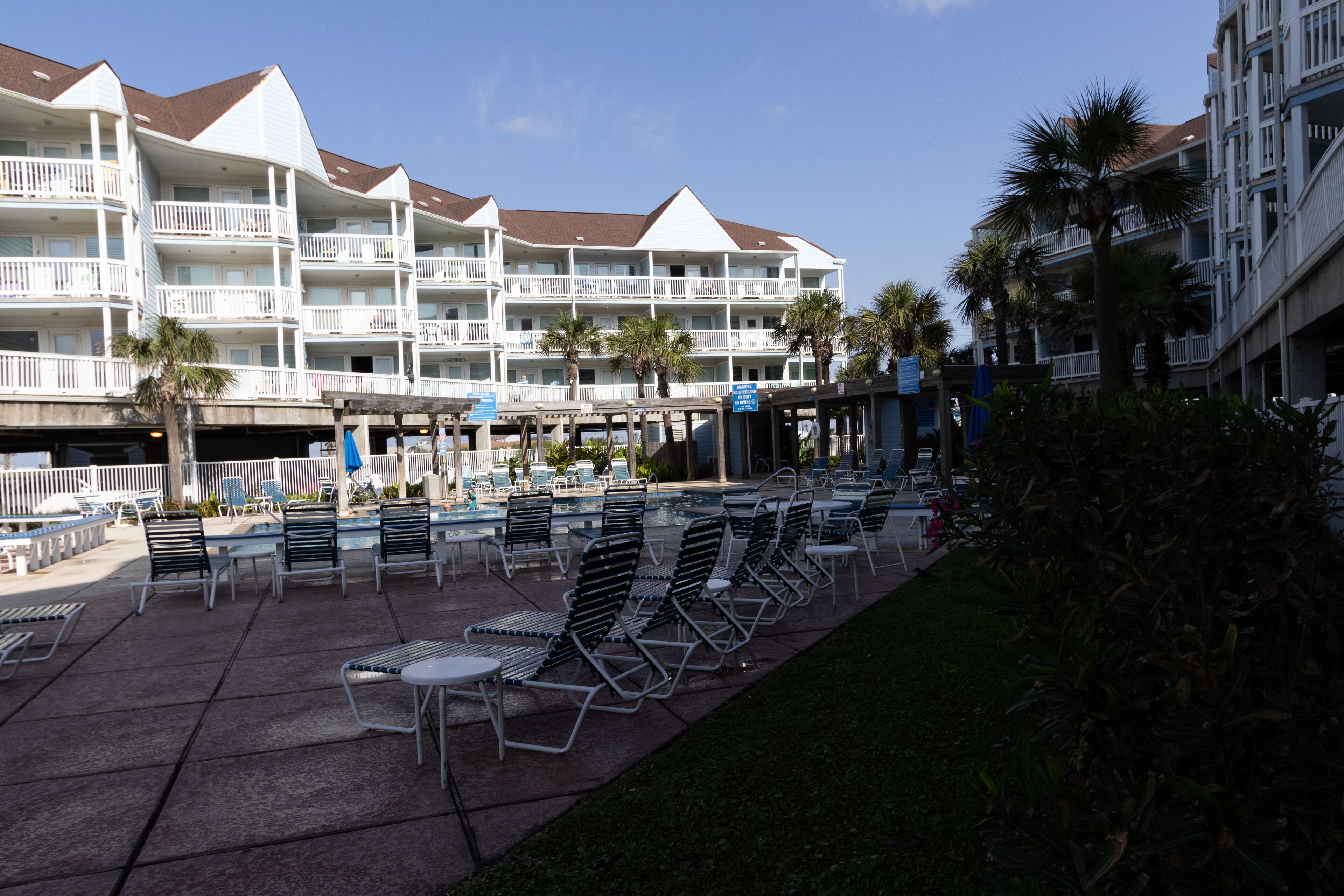 Un hotel con varios balcones, mobiliario exterior y una zona de piscina.