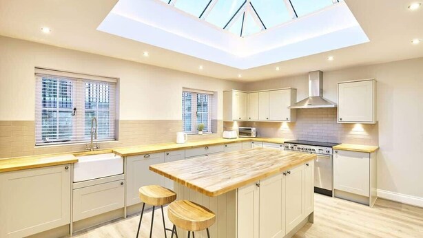 Una cocina moderna con tragaluz, taburetes de madera y una isla central.