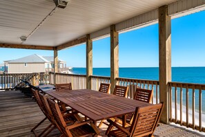 A wooden deck with a table and chairs, overlooking the ocean. - Beachfront, spacious with amazing indoor and outdoor setup! – Surf’s Up (Dauphin Island)
