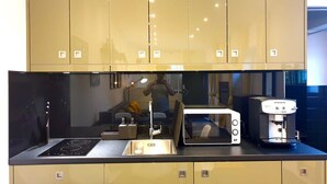 Et moderne køkken med en sort bordplade, rustfrie stålapparater og beige skabe.