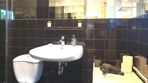 Et moderne badeværelse med en hvid vask, sorte fliser, et toilet og et spejl.