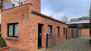 En murstensbygning med nummer 34, en lukket indgang og en brostensbelagt sti.