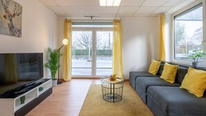 Een moderne woonkamer met een bank, televisie en een plant.