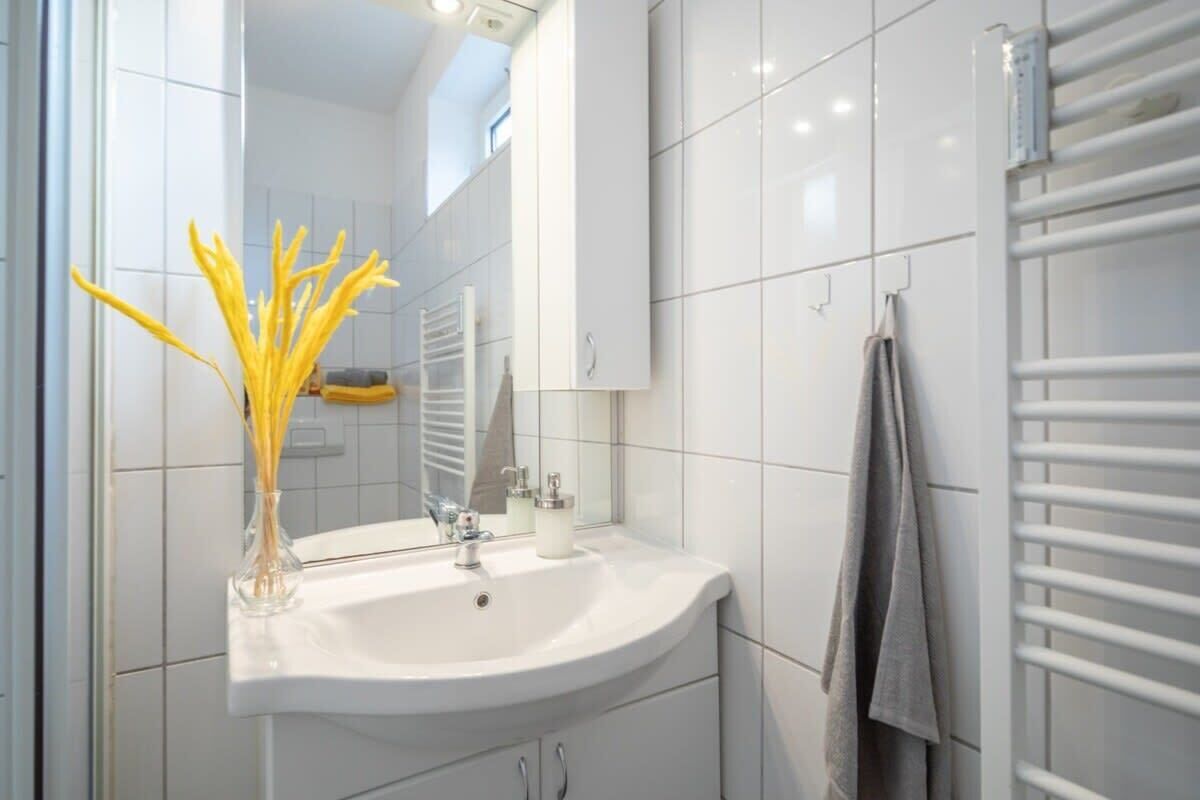 Een moderne badkamer met een wit wastafelmeubel, spiegel en handdoekhouder.