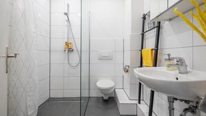 Un baño moderno con cabina de ducha de vidrio, inodoro blanco y lavabo con espejo.
