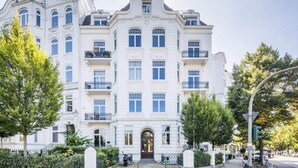 Un immeuble à plusieurs étages doté d’une façade symétrique, de grandes fenêtres et de balcons.
