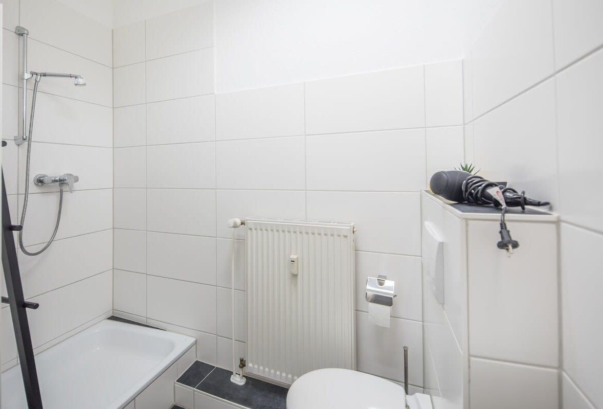 A small, modern bathroom with a bathtub, toilet, and shower.