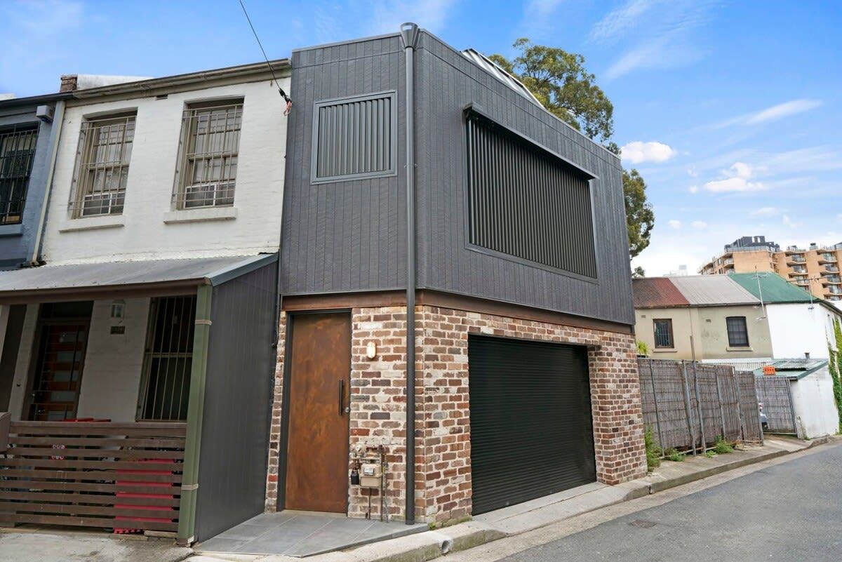 A modern building with a garage door, a brick facade, and a flat roof.