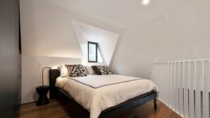 Ein Schlafzimmer mit Bett, Nachttisch, Lampe und Fenster.