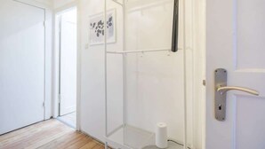 Een kamer met een douchecabine, een deur met een handgreep en een ingelijste foto aan de muur.