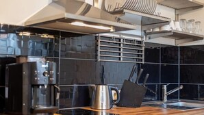 Une cuisine moderne avec des carreaux noirs, des appareils en acier inoxydable et des plans de travail en bois.
