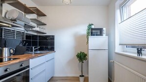 Une cuisine compacte équipée d’un four à micro-ondes, d’un réfrigérateur et d’un plan de travail en bois.