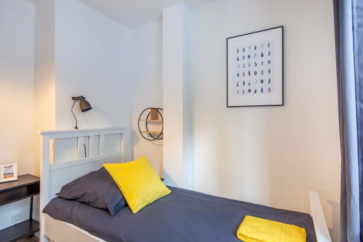 A bedroom with a bed, a bedside table, a lamp, and a framed picture on the wall.
