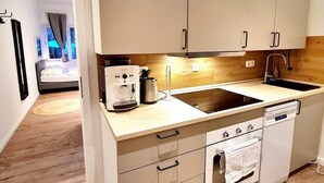 A modern kitchen with light wood cabinetry, a built-in oven, and a dishwasher. - Apartment 1 Hamburg Winterhude (Hamburg)