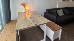 A modern living room with a wooden coffee table, a white side table, and a dark sofa. - Apartment 1 Hamburg Winterhude (Hamburg)