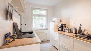 Una cocina moderna con encimera negra, armarios blancos, una ventana y un radiador.