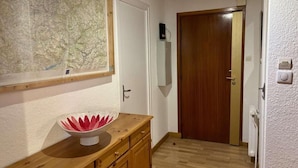 A hallway with a wooden cabinet, a map on the wall, and a wooden door.