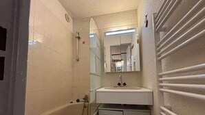 A bathroom with a bathtub, a sink, and a mirror. - 100m from resort center, 1st floor, balcony, tv, 25m², Alpe d'Huez (L'Alpe d'Huez)