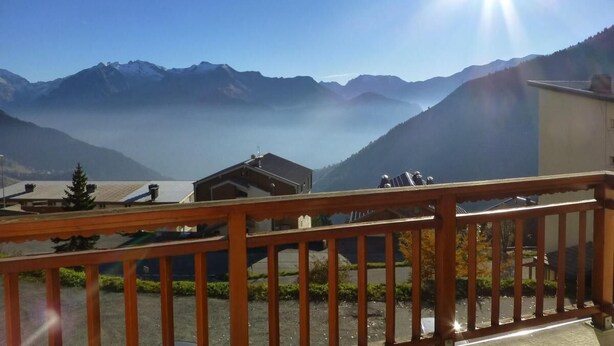 Een balkon met uitzicht op een berglandschap en een meer.