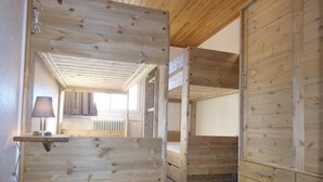 Een houten interieur met stapelbedden, een tafeltje met een lamp en een radiator.