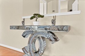 Una consola moderna con un espejo decorativo y una planta en maceta.