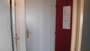 A closed door with a brass handle, a red wall, and a white door frame. - 80m from shops, 4th floor, balcony, tv, ski locker, 23m², Alpe d'Huez (L'Alpe d'Huez)
