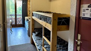 Una stanza con letti a castello, uno scaffale in legno e una porta con un codice QR.