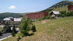 Un albergo con diversi piani, una seggiovia e montagne sullo sfondo.