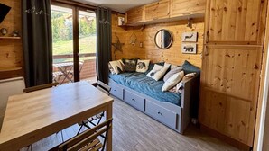 Un accogliente rifugio con interni in legno, un letto con molti cuscini, un tavolo da pranzo e un'ampia finestra con tende.